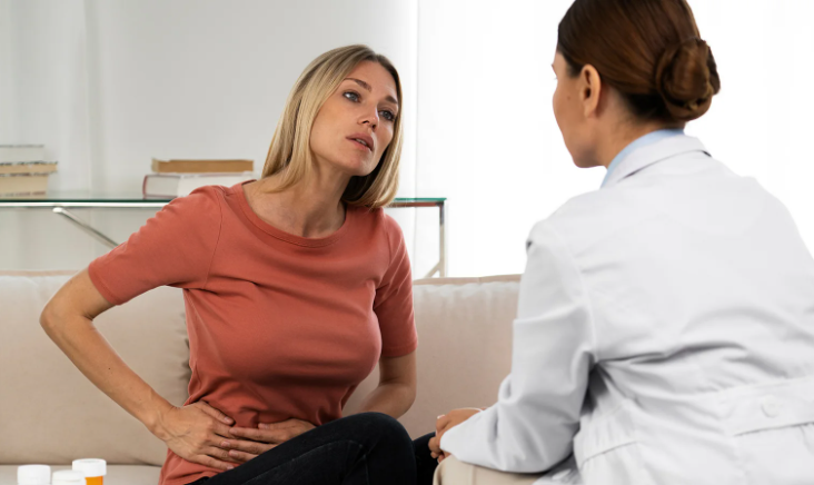 Woman holding her painful side while consulting with a doctor.