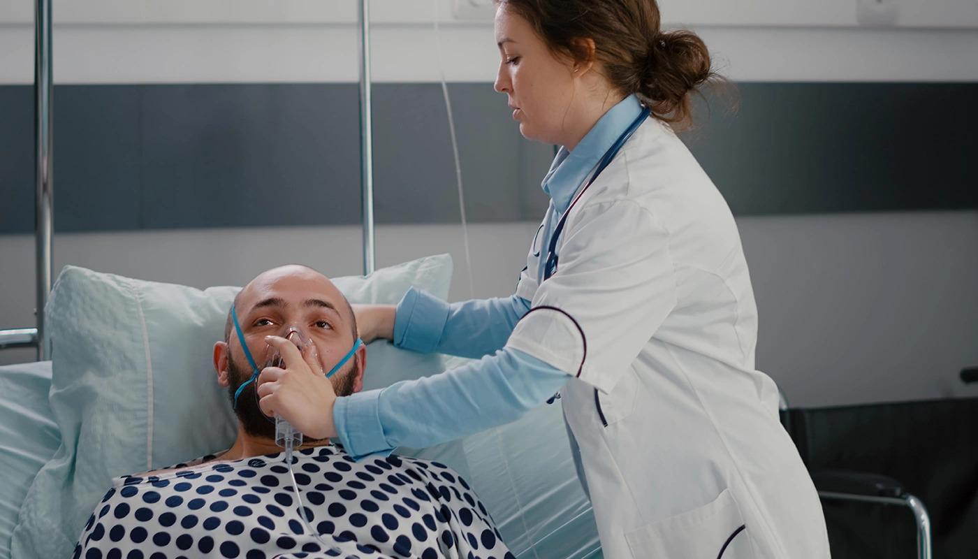 Doctor placing an oxygen mask on a patient in hospital.